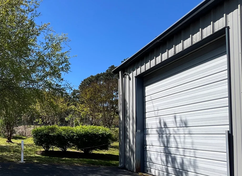 A roll-up bay door at United Flex Toano, unit 22, beside a lawn and trees